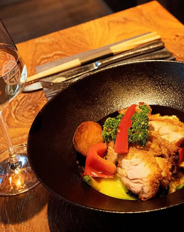 Crispy Chicken mit Gemüse in schwarzer Schale